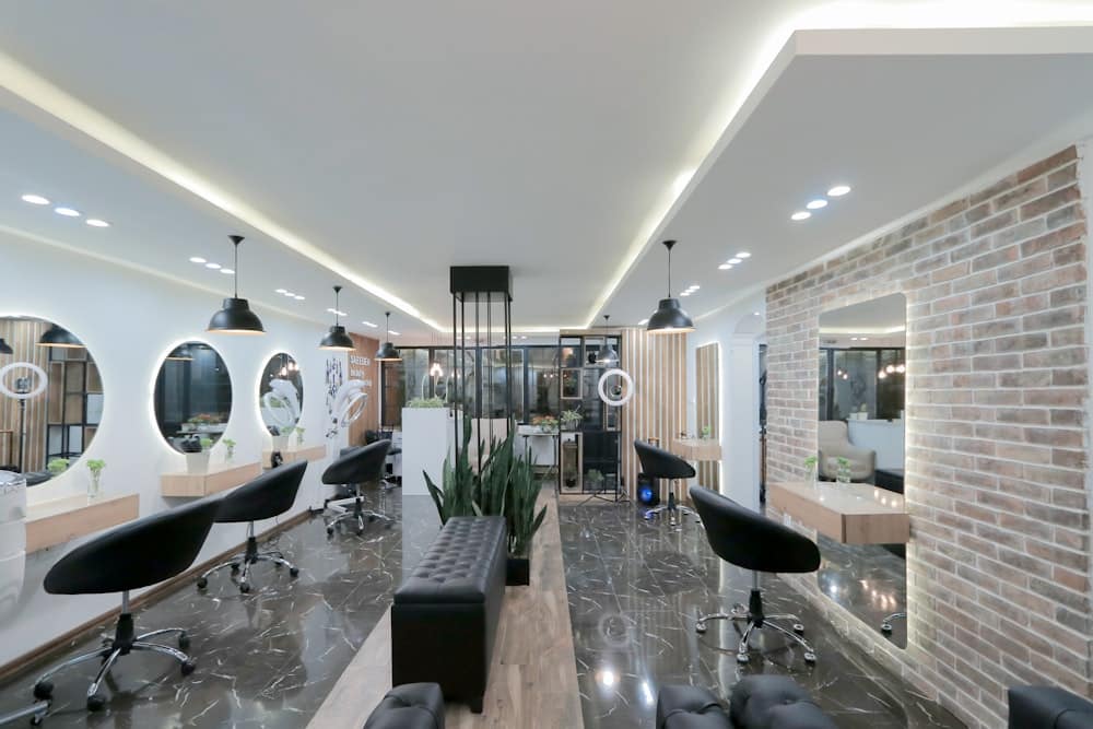 Aydınlık, ferah salon iç mekânı; aynalar, bitkiler ve tuğla duvar