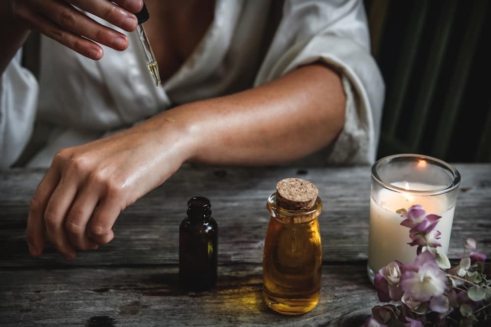 Ahşap masada aromaterapi yağı, mum ve çiçekler